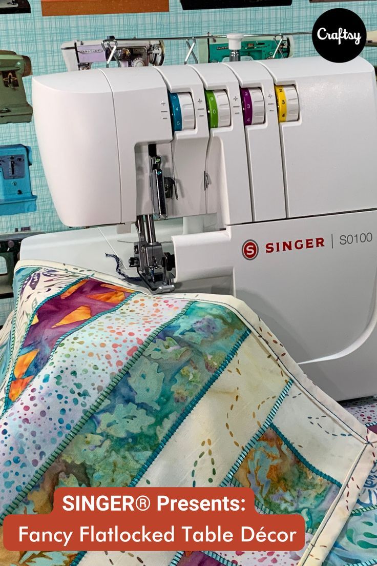 a sewing machine sitting on top of a table next to a quilted coverlet