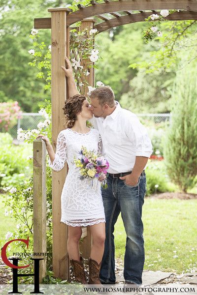 a man and woman standing next to each other in front of a gazebo with flowers on it