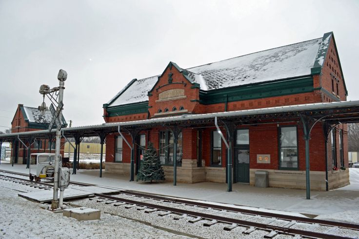 an old train station with snow on the ground and tracks in front of it,