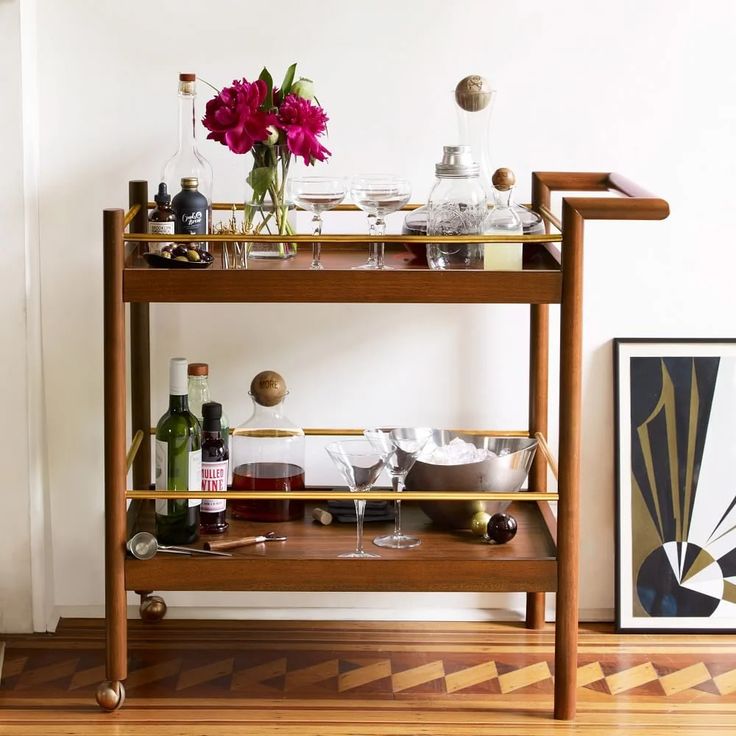 a bar cart with wine glasses and bottles on it