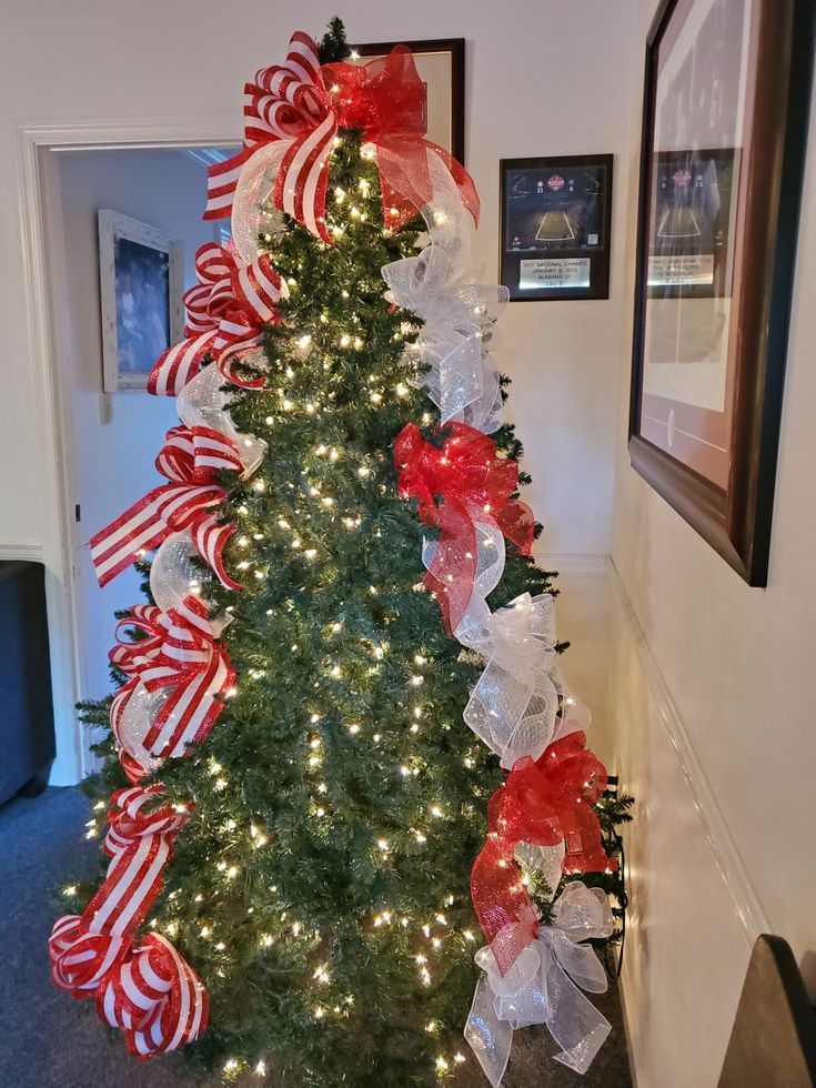 a decorated christmas tree with red and white bows