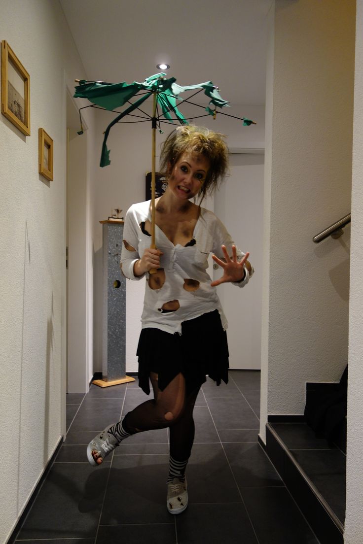 a woman in white shirt and black skirt running down hallway with umbrella above her head