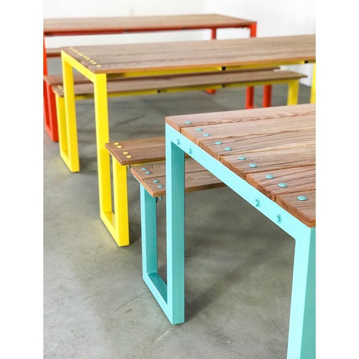 three wooden benches sitting next to each other on cement floored area with white walls