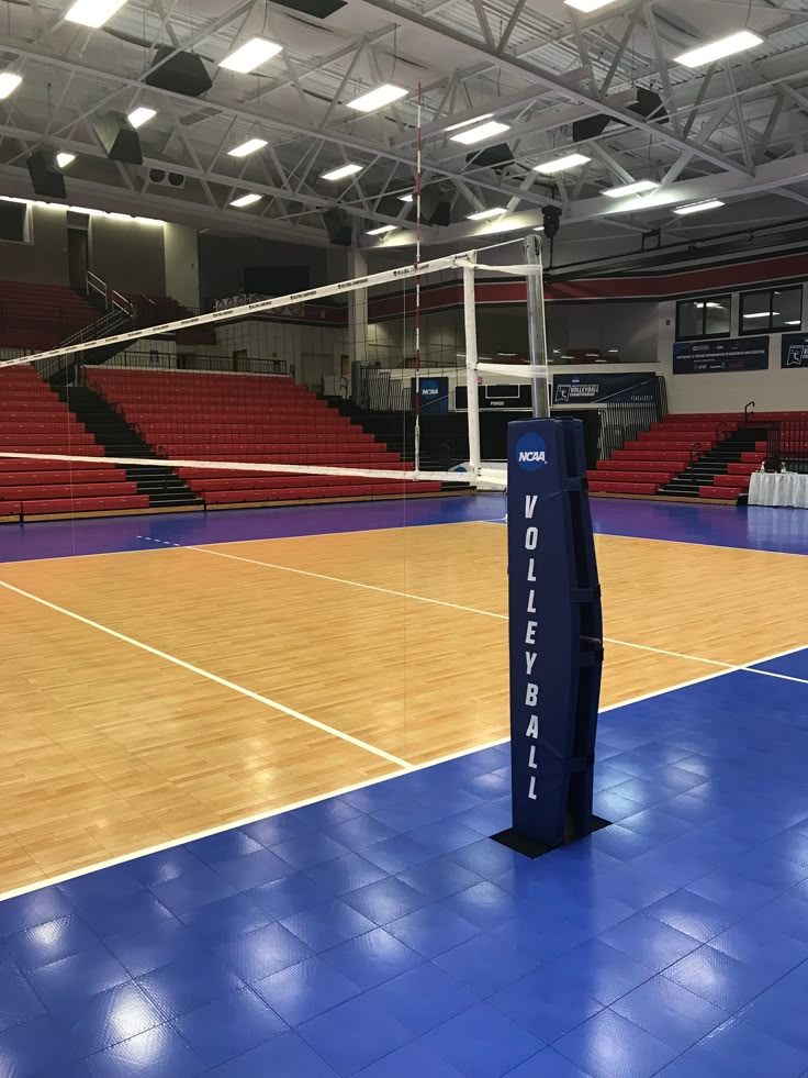 an indoor volleyball court with blue tiles and red seats