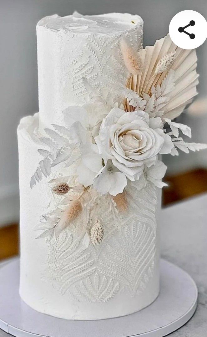 a white wedding cake decorated with flowers and feathers