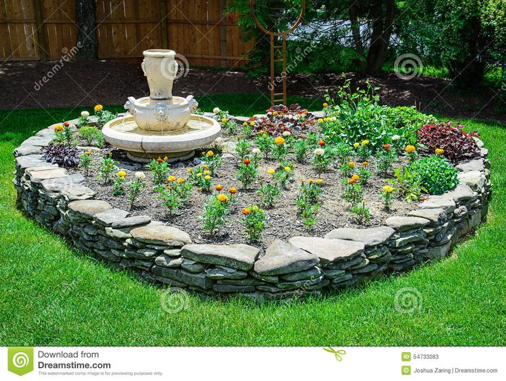 a garden with flowers and a fountain in the middle