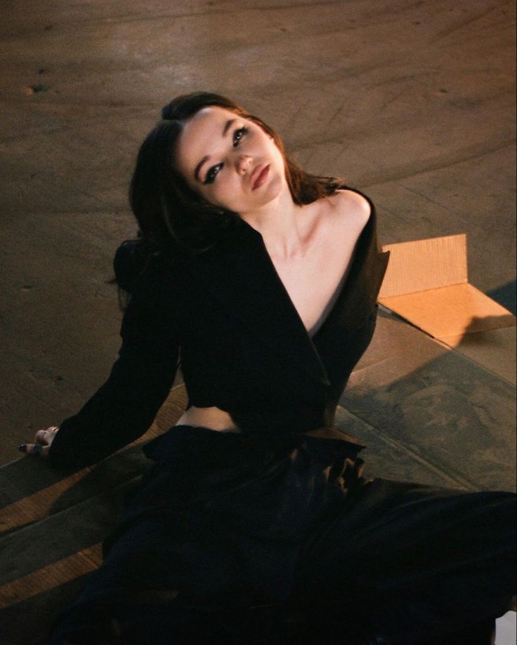 a woman sitting on the ground in a black dress