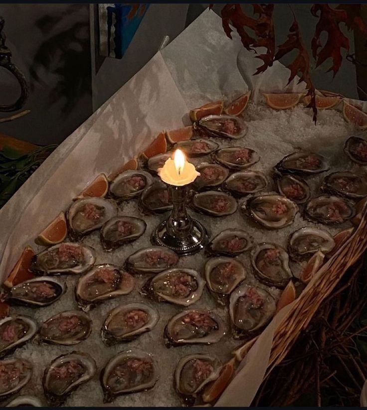 a basket filled with lots of oysters next to a lit candle