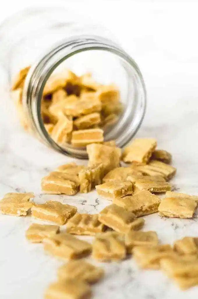 a glass jar filled with pieces of food on top of a white countertop next to a pile of cut up bananas