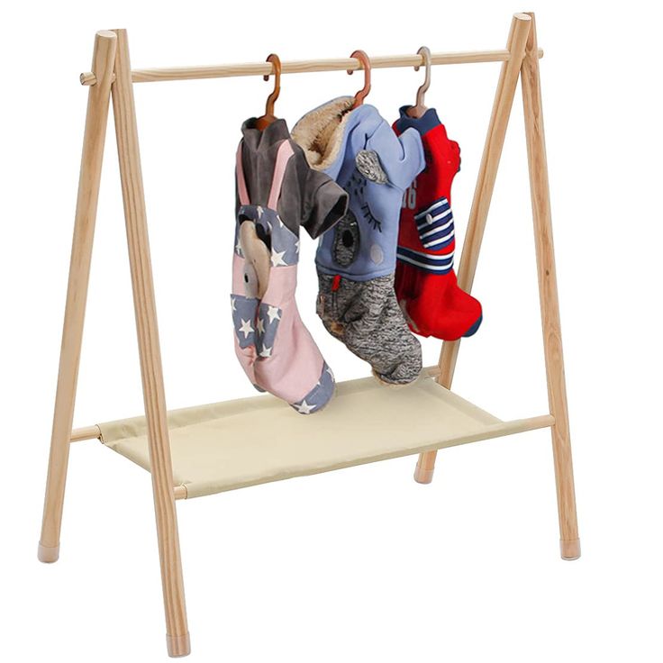 two children's clothes hanging on a wooden rack with shoes and socks in them