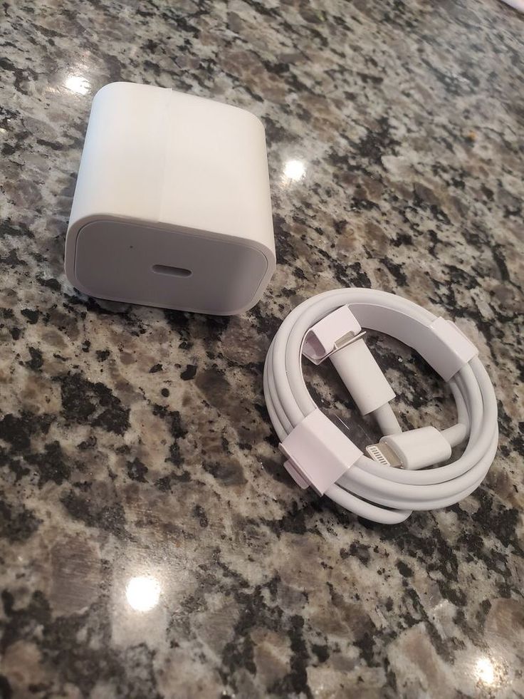 an apple charger sitting on top of a counter next to a usb cable and adapter