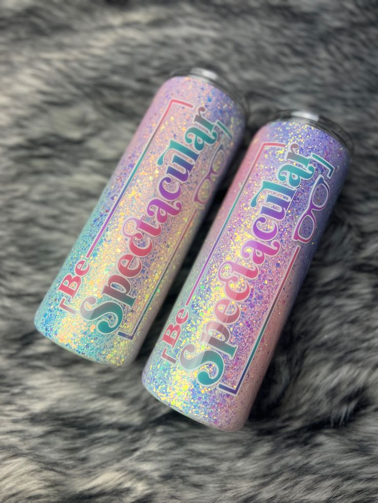 two rainbow colored cans sitting on top of a furry surface