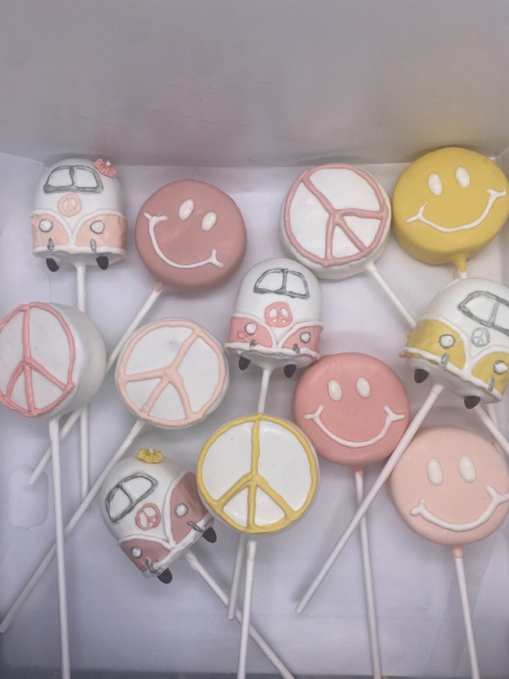 a box filled with lots of cake pops covered in frosting and smiley face designs