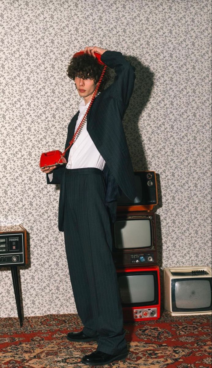 a young man standing in front of an old tv set with his hands on his head