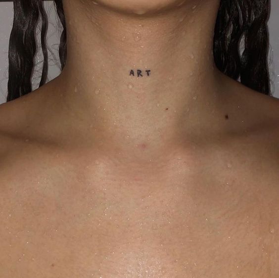 a woman's chest with the word art tattooed on her left side, in black ink