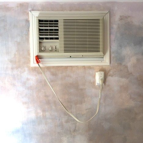 a wall mounted air conditioner on the side of a wall with a cord attached to it