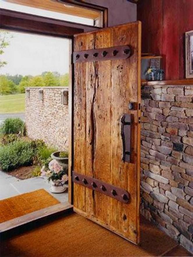 an open wooden door in front of a brick wall and stone fireplace with potted plants next to it