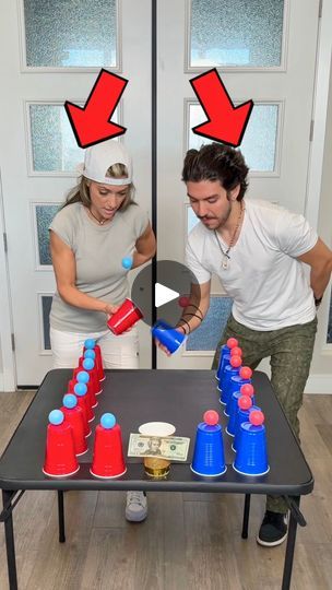 a man and woman standing in front of a table full of cups with one person pouring something into the cup