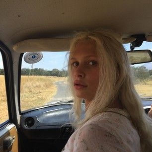 a blonde woman sitting in the passenger seat of a car looking out the back window