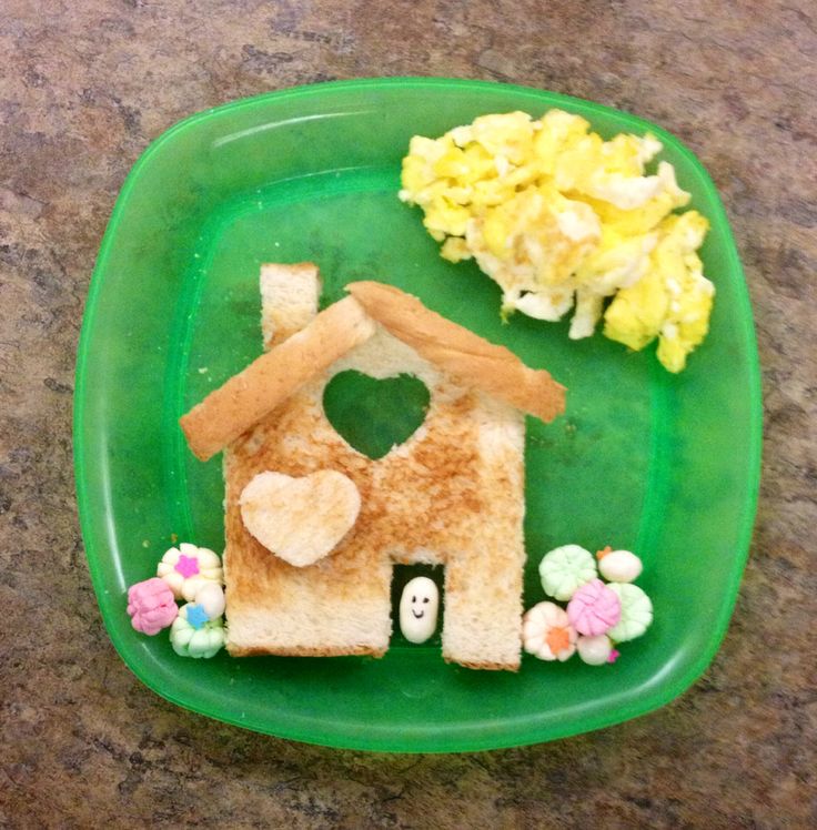 a green plate topped with a house shaped sandwich next to some flowers and other items