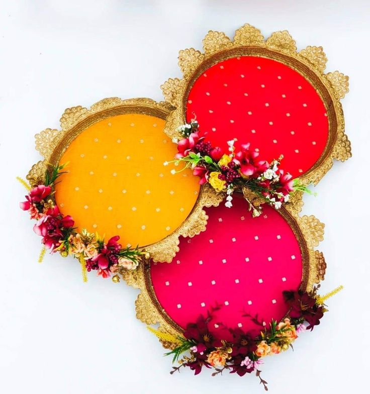 three circular trays decorated with flowers and gold rimmed frames on a white background