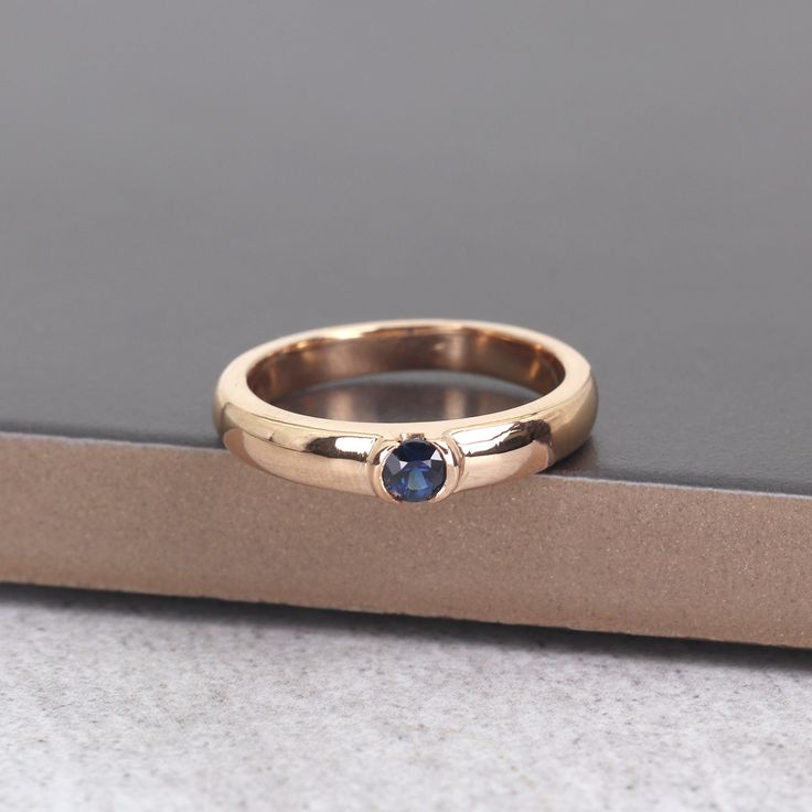 a gold ring with a blue stone in the center on top of a cardboard box