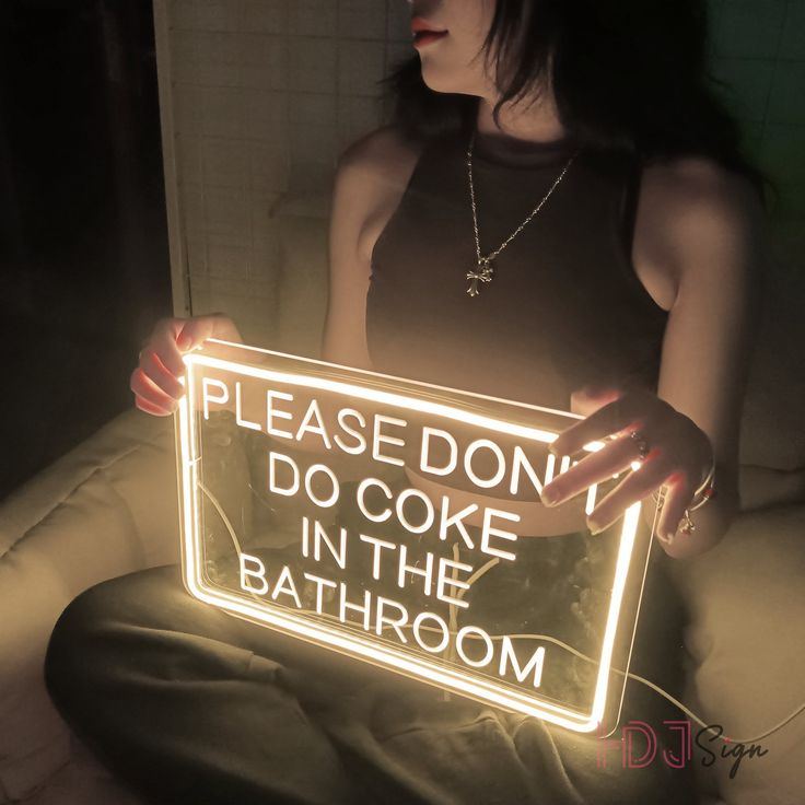 a woman holding a sign that says please don't do coke in the bathroom