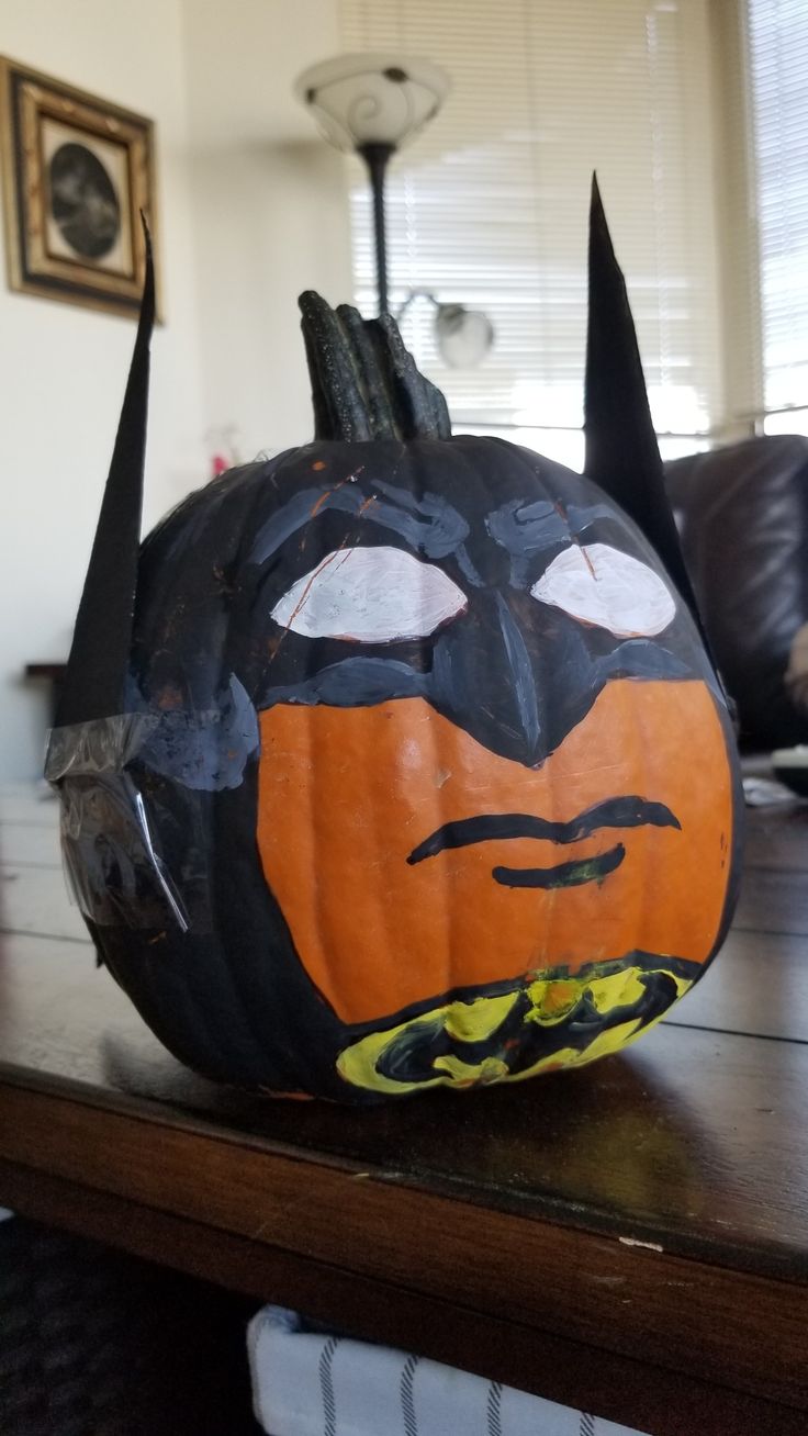 a batman pumpkin sitting on top of a wooden table