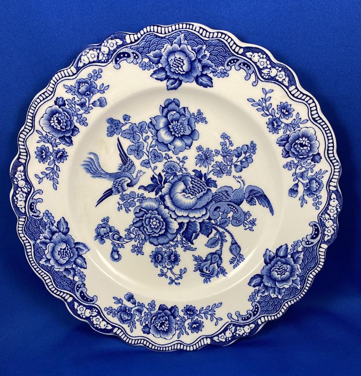 an ornate blue and white plate with birds on it's rim, against a blue background