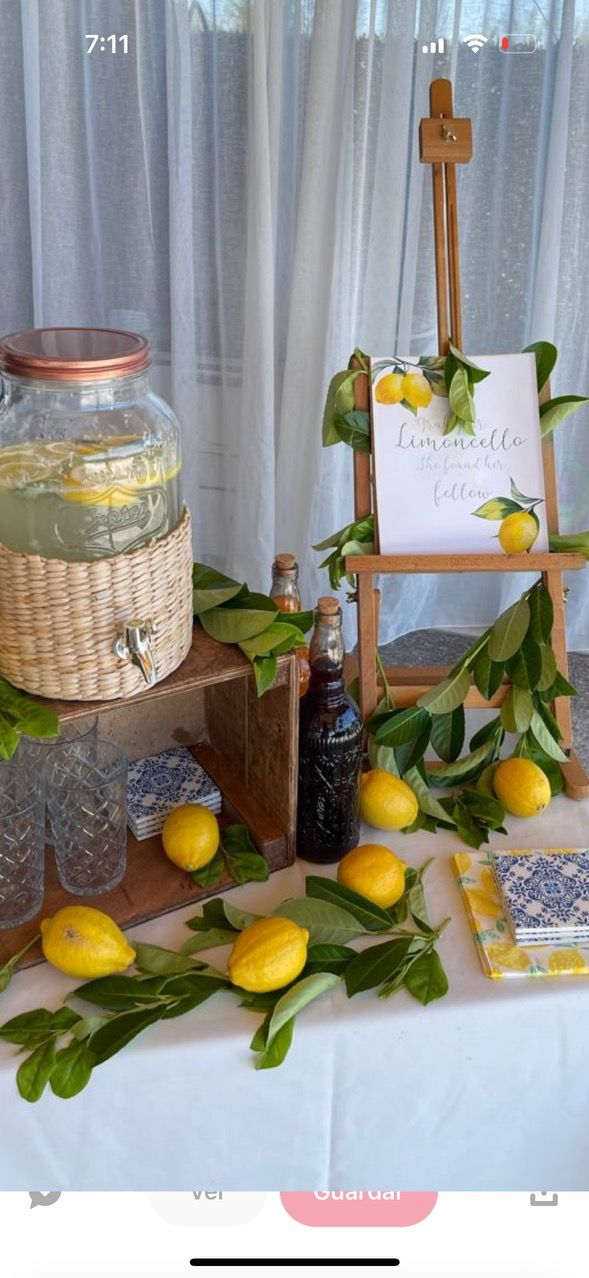 a table topped with lemons next to a sign and glass jar filled with liquid