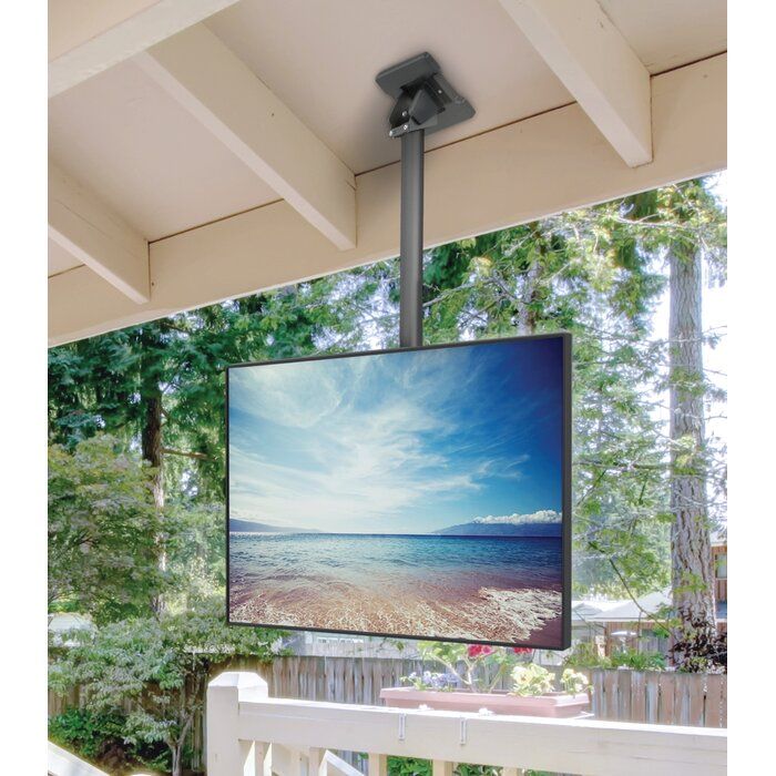 a flat screen tv mounted to the side of a wooden porch next to a white fence