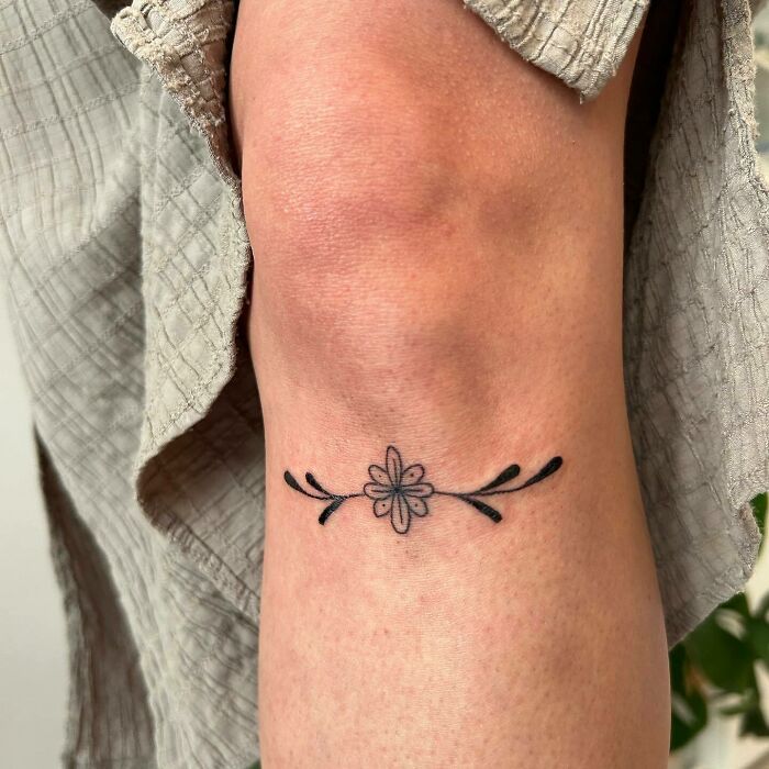 a woman's arm with a small flower tattoo on the left side of her leg