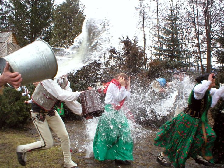 some people are dancing in the water with buckets on their heads and one person is holding a box