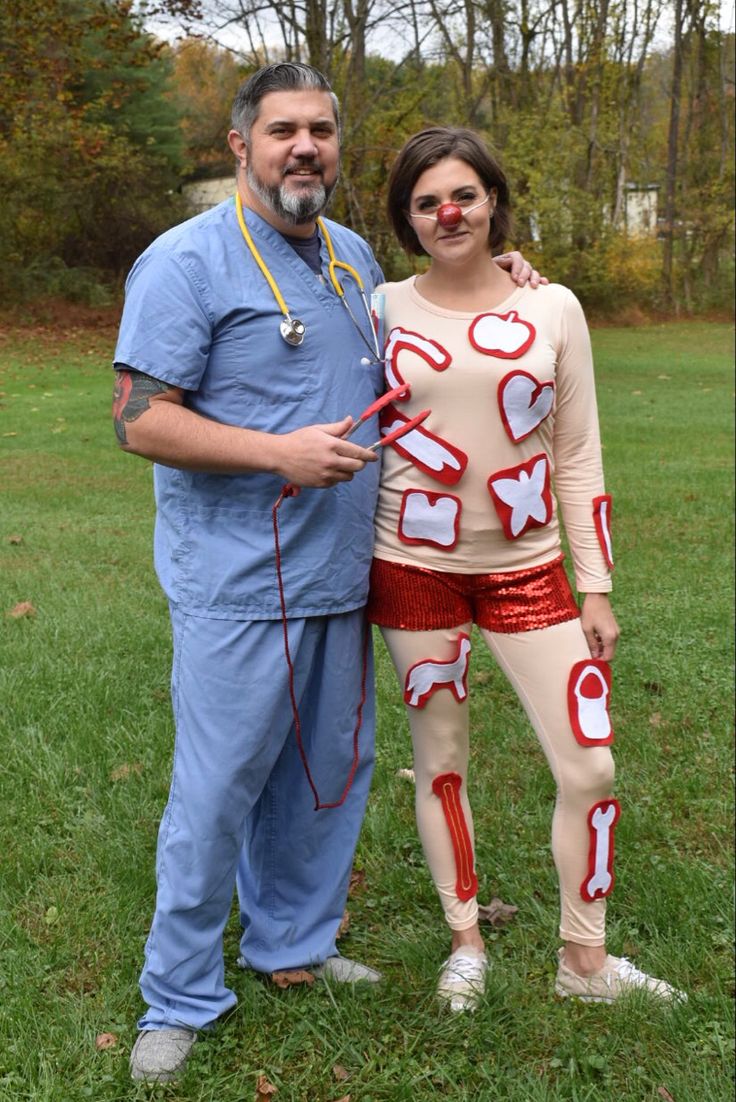 a man standing next to a woman in costume on top of a grass covered field