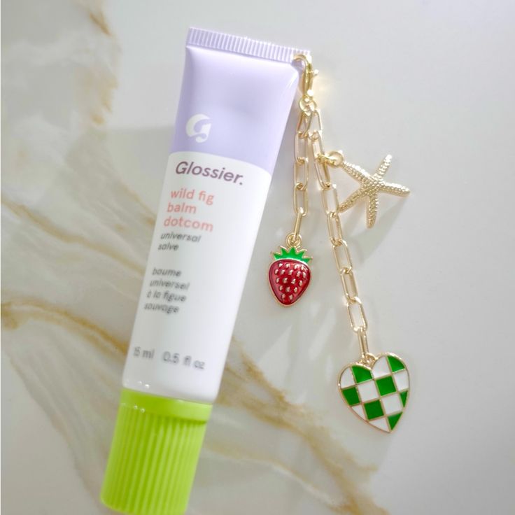 a tube of toothpaste next to a charm on a white surface with gold chain