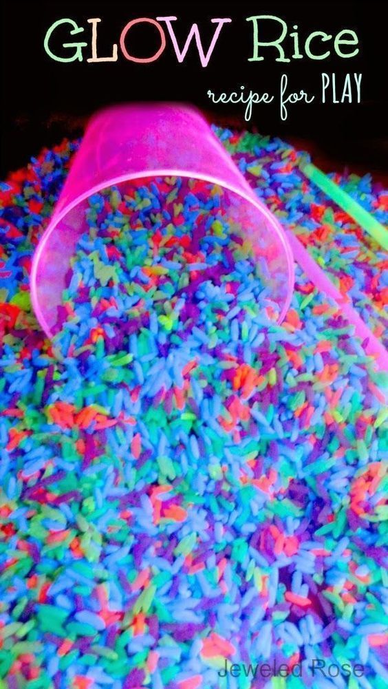 a plastic bucket filled with colorful rice next to a neon colored straw and green straw