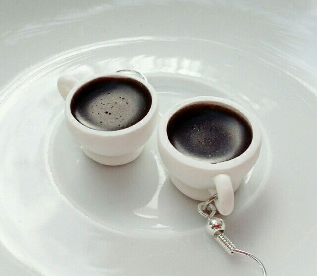 two cups of coffee sitting on top of a white plate with a spoon in it