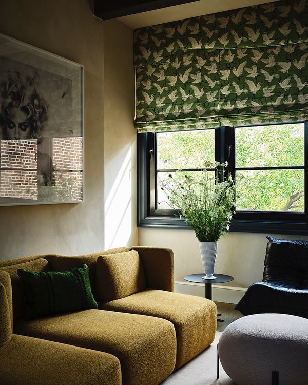 a living room filled with furniture and a window covered in green curtains next to a chair