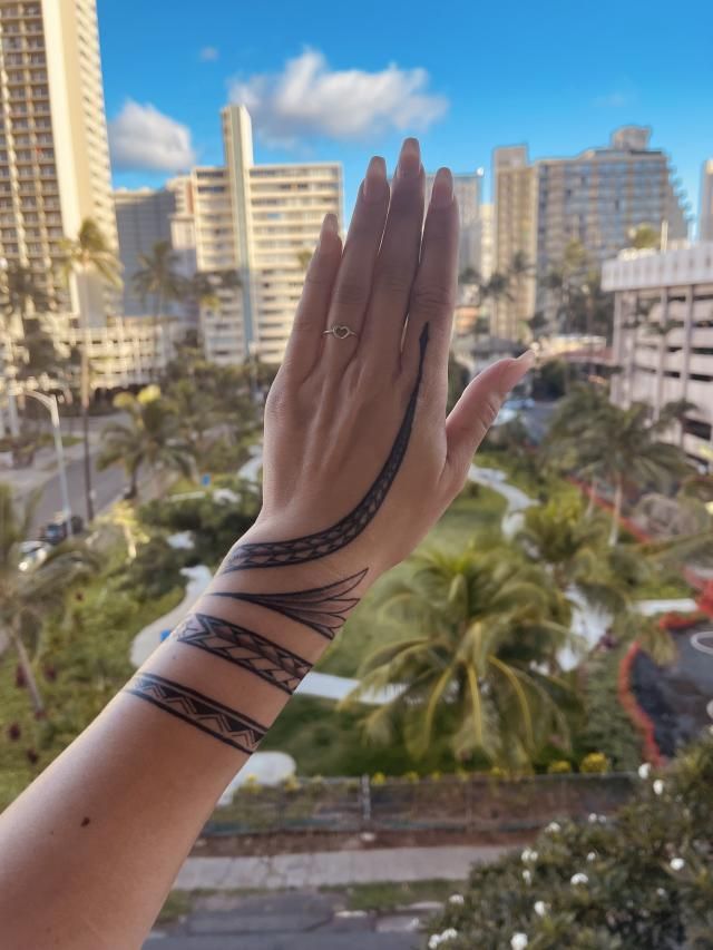 a woman's arm with tattoos on it and palm trees in the background