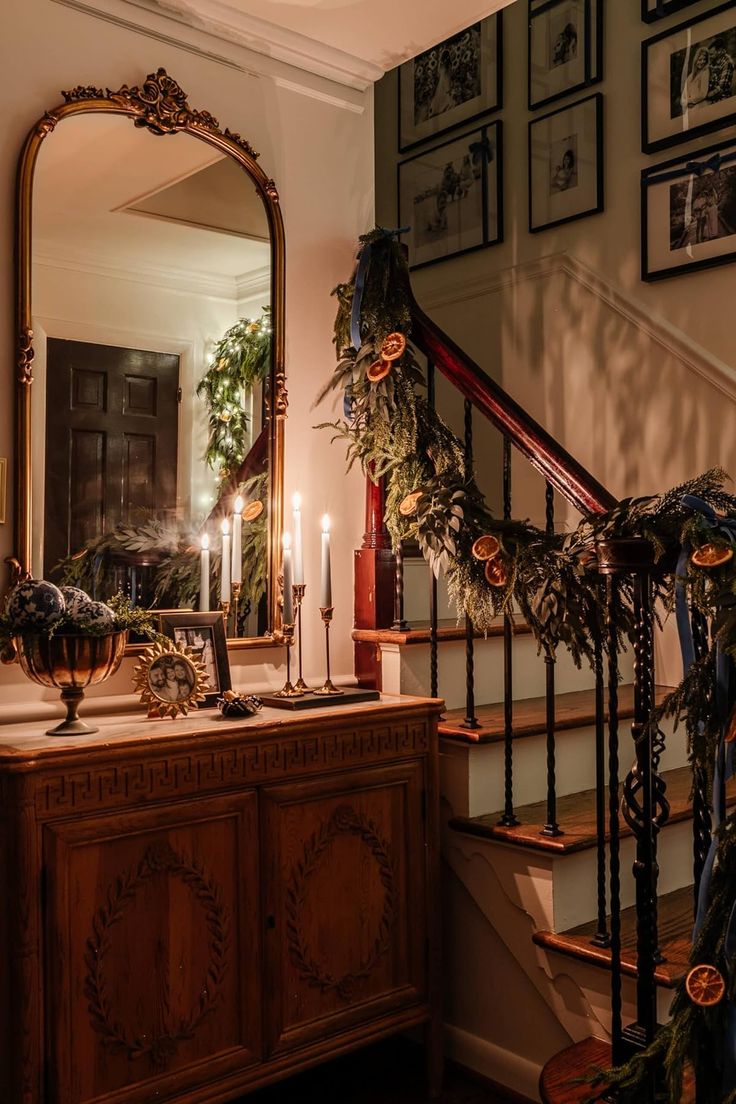 a staircase decorated with greenery and candles in front of a mirror on the wall