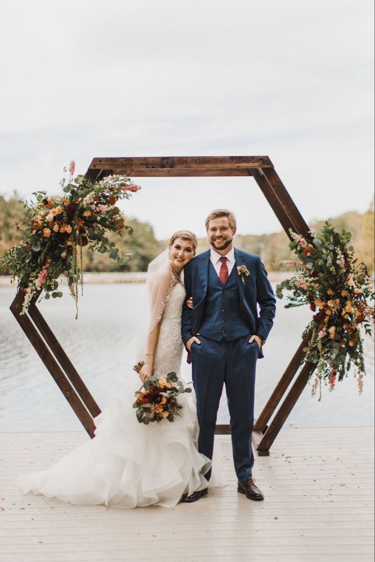 a bride and groom standing in front of a wooden frame