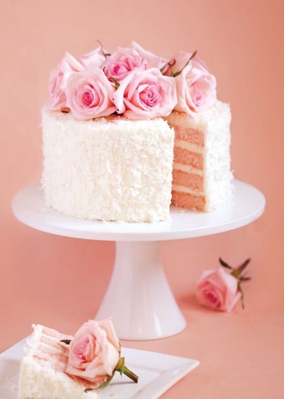 a cake with white frosting and pink flowers on top is sitting on a plate