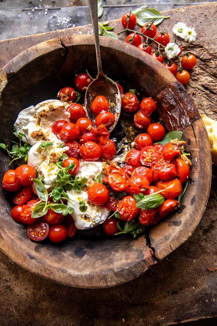 a wooden bowl filled with tomatoes and cheese