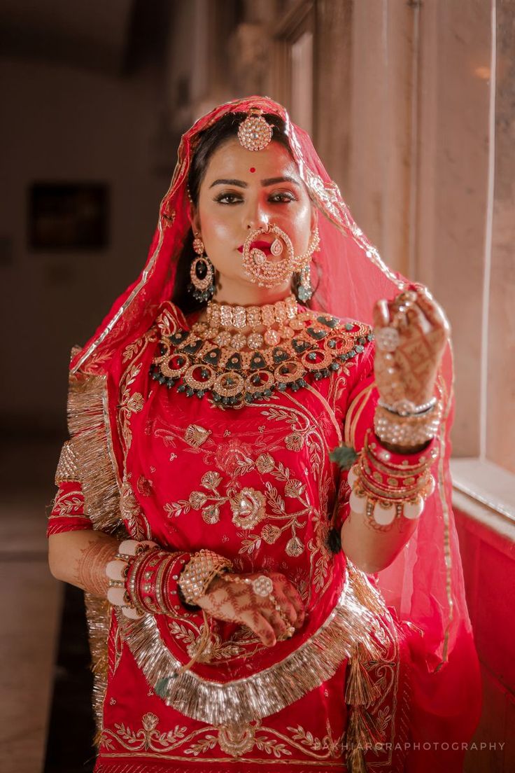 a woman dressed in red and gold poses for the camera