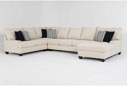 a white sectional couch with black and gray pillows on the bottom half, sitting in front of a white wall