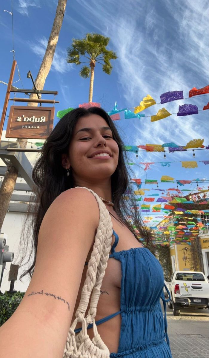 a woman in a blue dress is holding onto a white bag with colorful flags hanging from it