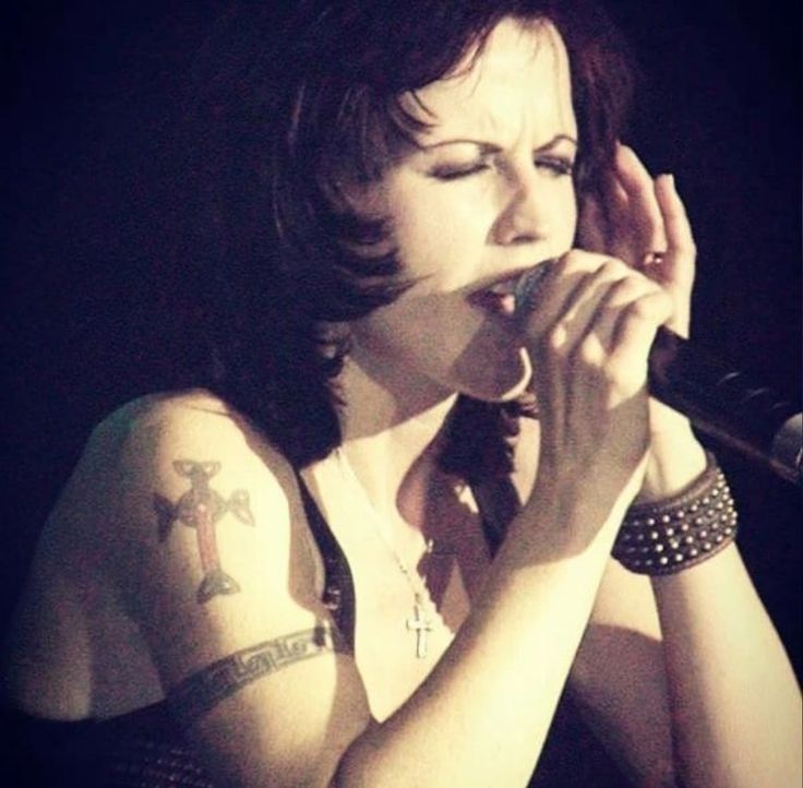 a woman with tattoos on her arm singing into a microphone