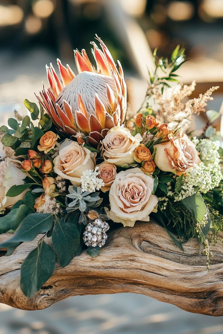 an arrangement of flowers on a piece of driftwood