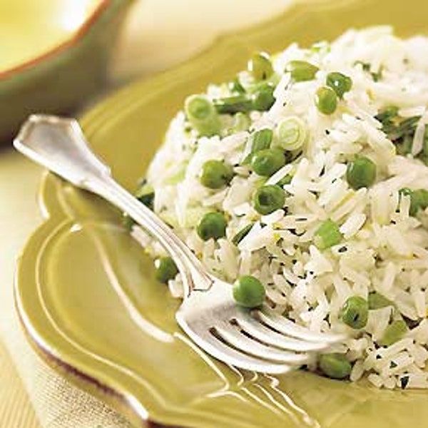 rice and peas are served on a green plate with a silver fork next to it