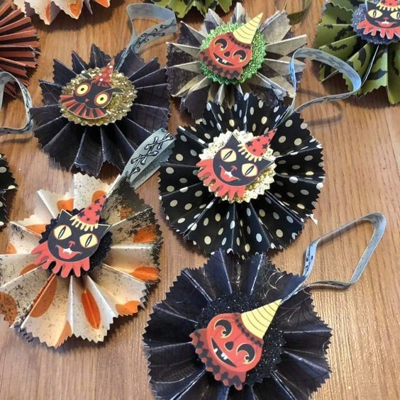 several different types of paper flowers on a wooden table with ribbons and decorations around them